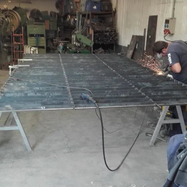 Un hombre está soldando una gran pieza de metal en un taller.