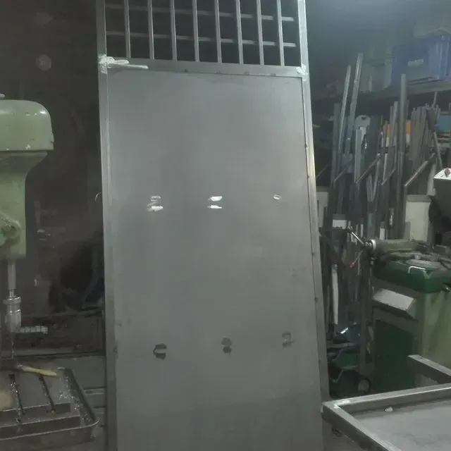 Una gran puerta de metal se encuentra en un taller al lado de una máquina verde.