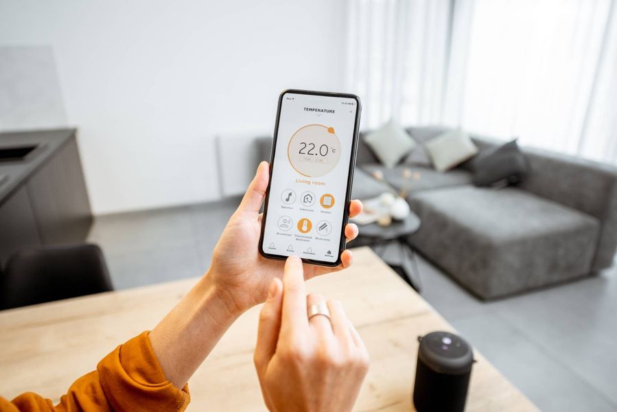 Hände halten ein Smartphone, auf dem die Temperatur angezeigt wird