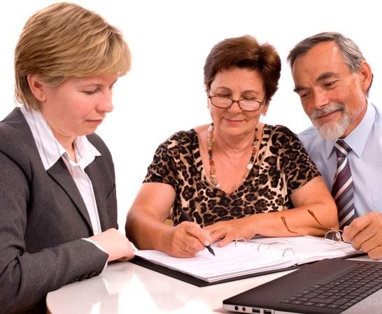 Tres compañeros revisando documentos juntos frente a un portátil en una oficina