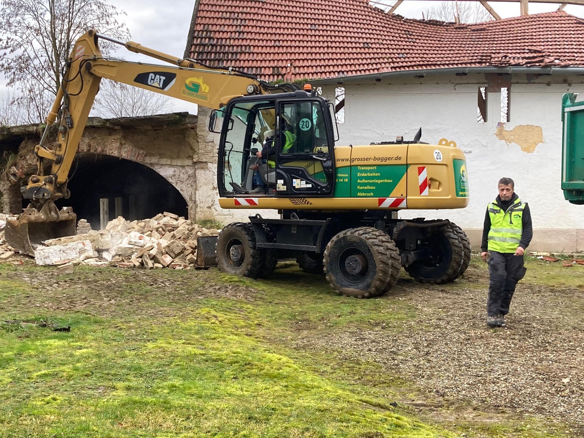 Ein Bagger führt Abbrucharbeiten durch und entfernt Ziegelsteine.