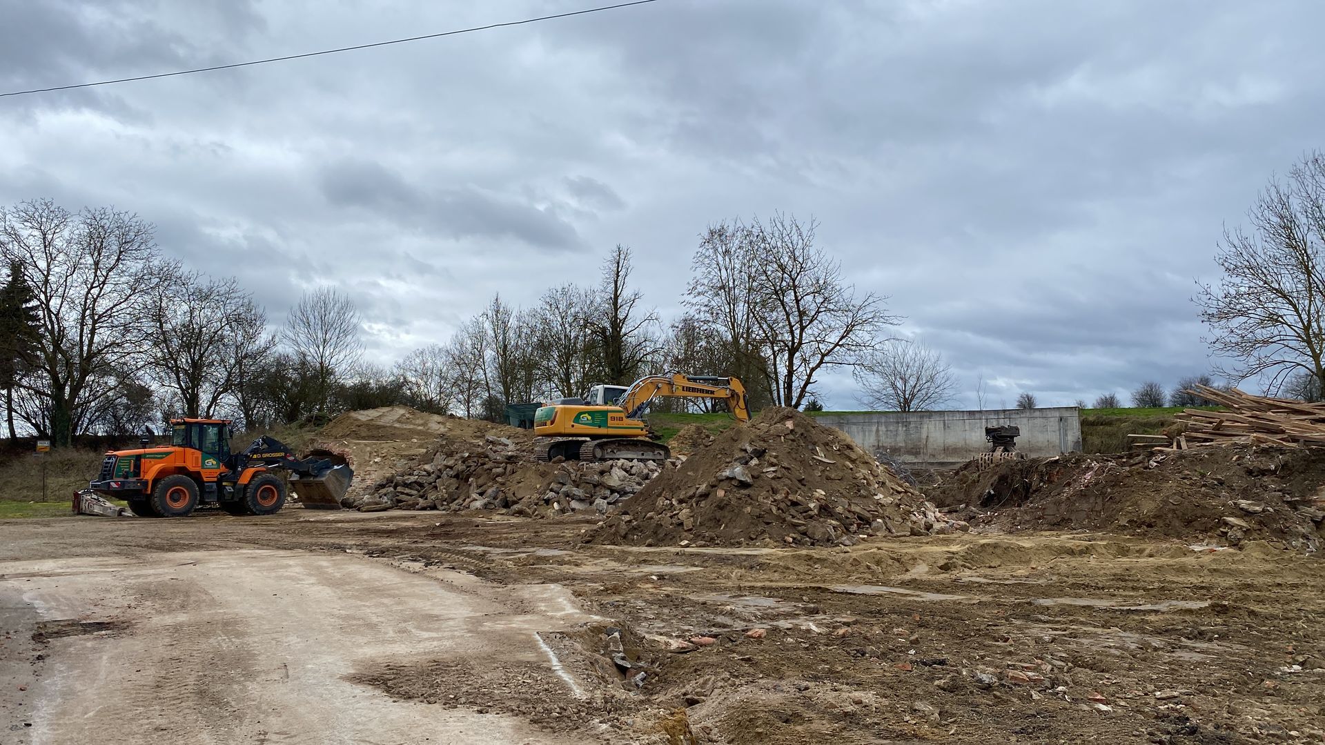 Baustelle mit Bagger und Lkw auf einem Erdhaufen.