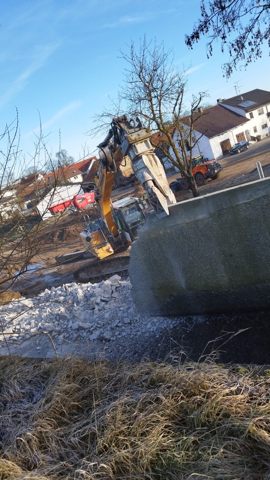 Eine Baumaschine führt Abrissarbeiten an einer Betonfläche durch.