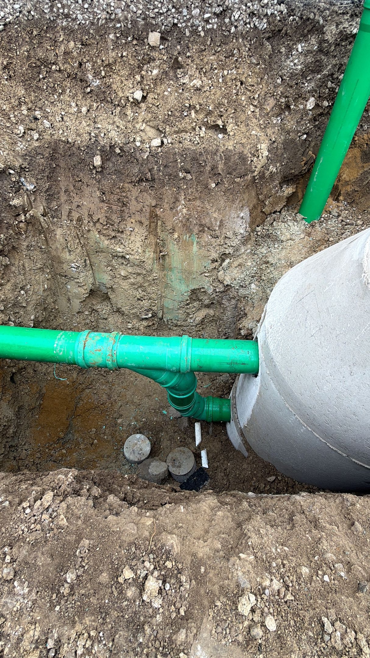 Sicht auf grüne Rohre und Betonbehälter im Erdreich