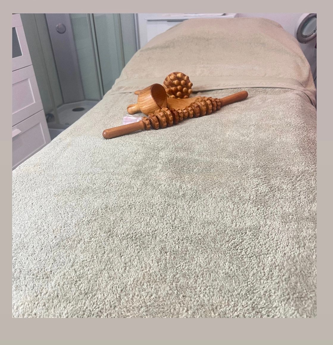 En una sala de spa, sobre una camilla cubierta con una toalla, se encuentran herramientas de madera para masajes