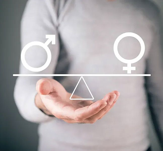 Una persona sostiene una balanza con símbolos de género masculino y femenino en cada lado, que representan la igualdad de género.