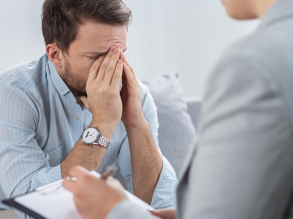 Hombre con la cabeza entre las manos, sentado durante una sesión de terapia.