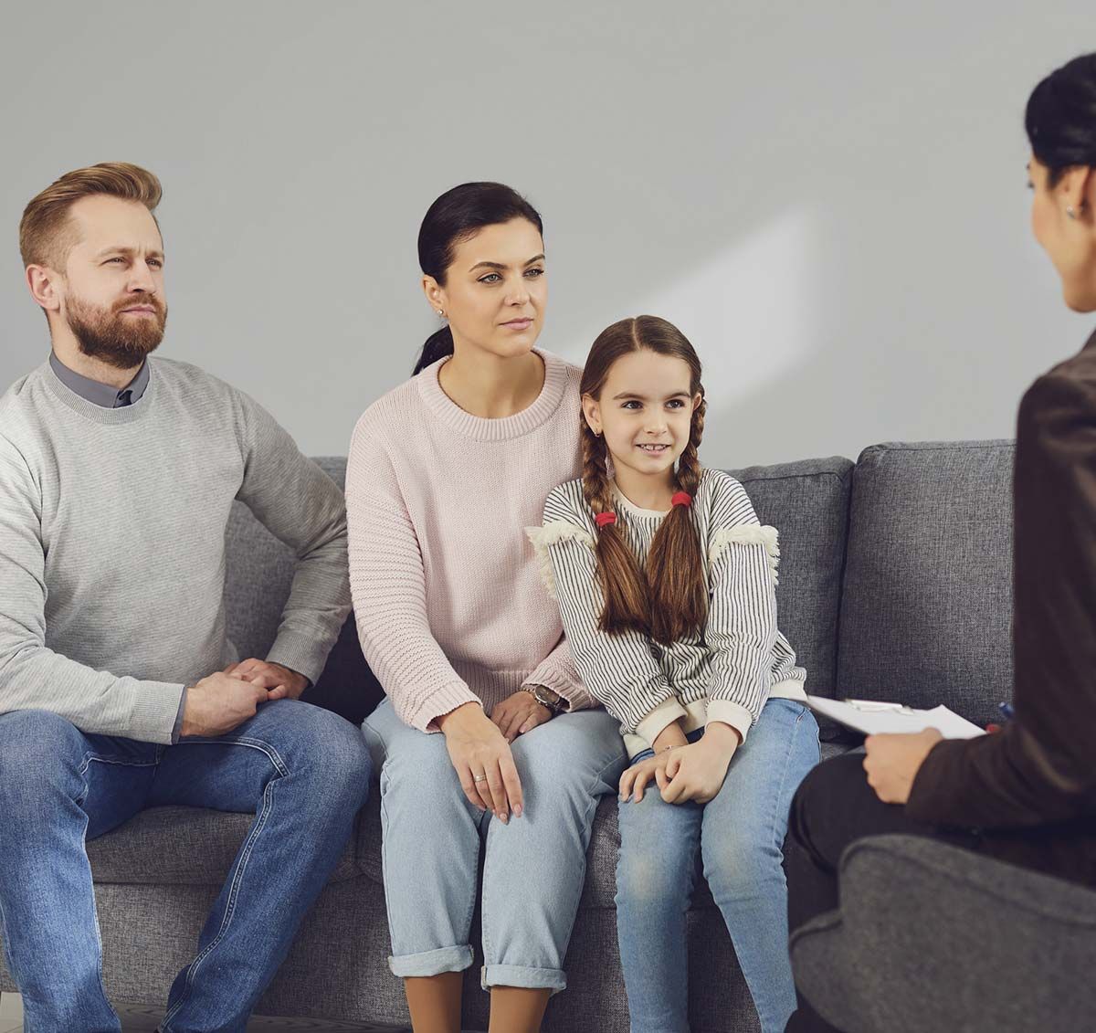 Una familia sentada en un sofá, hablando con un terapeuta.