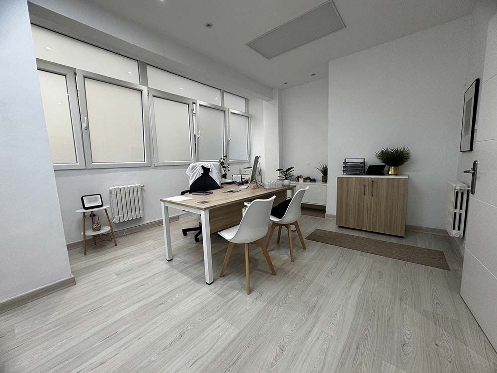 Oficina luminosa con escritorio, sillas, ventana, armario y radiador.