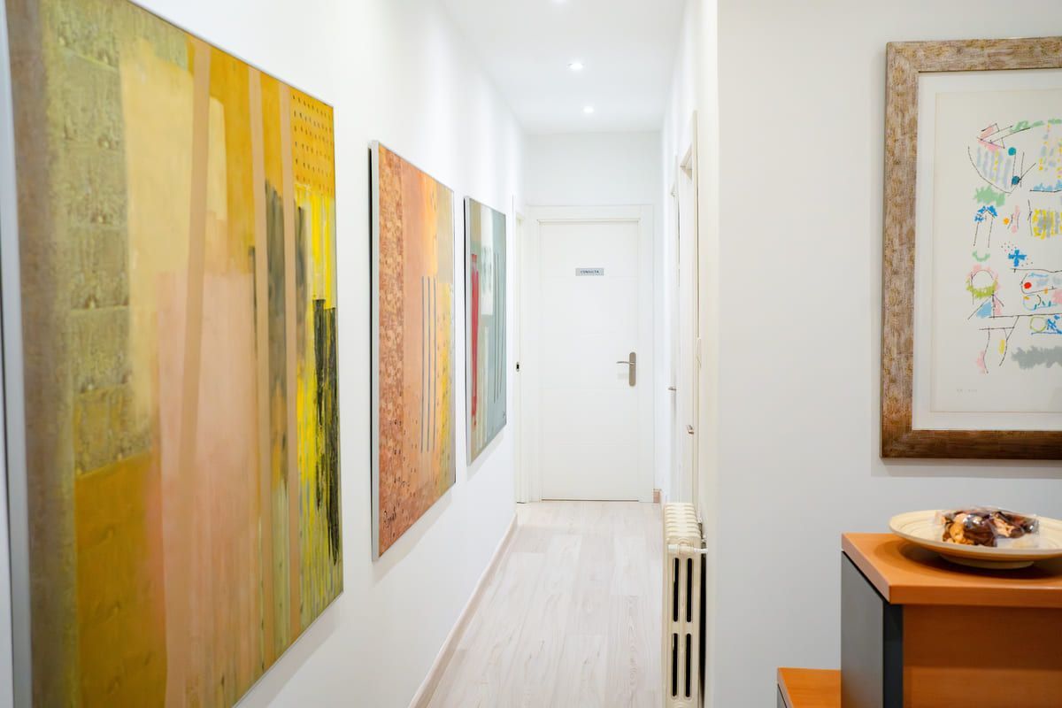 Un largo pasillo con arte abstracto en las paredes y una puerta al final.