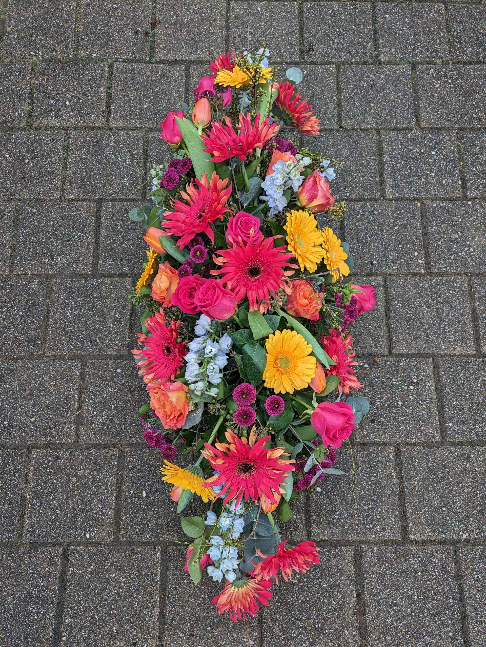Länglicher Blumenstrauß mit dicht angeordneten Blüten auf Pflasterboden