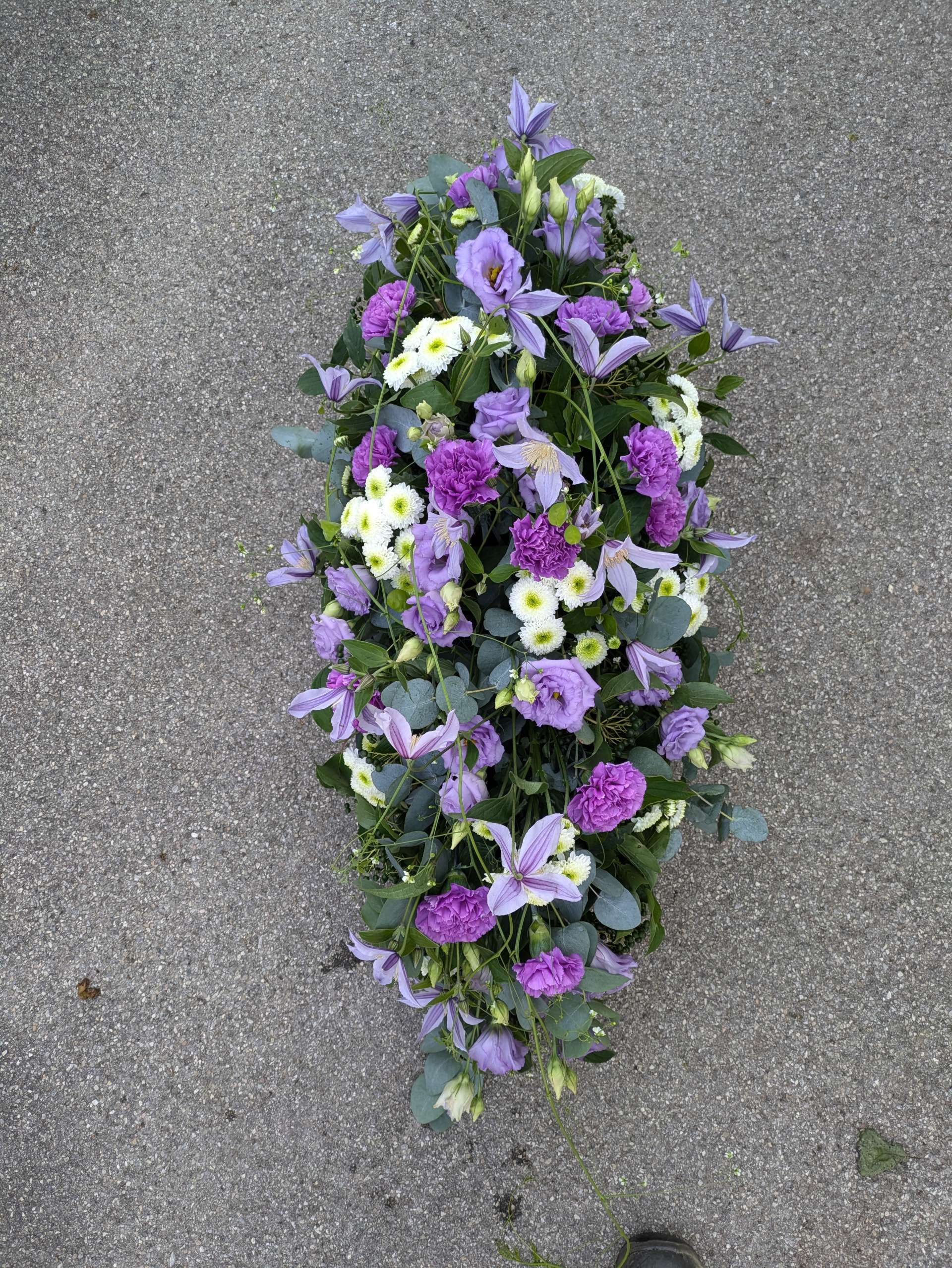 Blumenstrauß mit länglicher Form und verschiedenen Blüten auf einer Oberfläche
