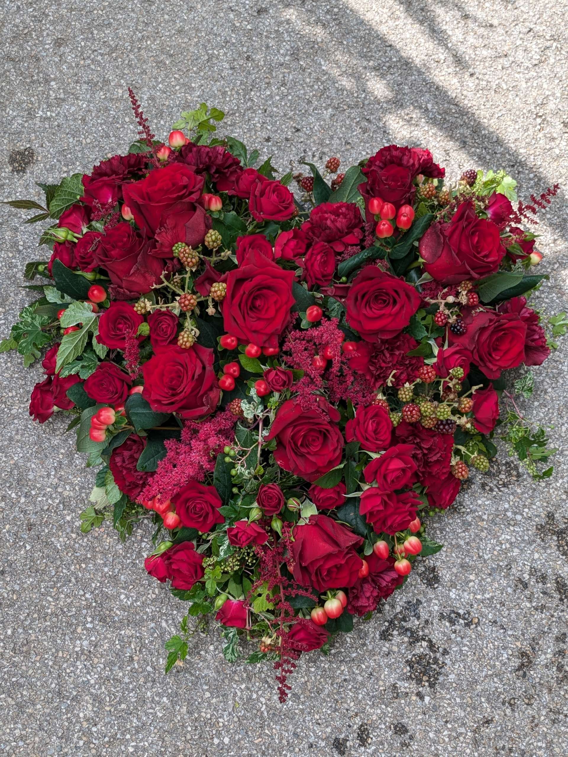 Blumenarrangement mit roten Rosen und weiteren Blüten auf einer Oberfläche