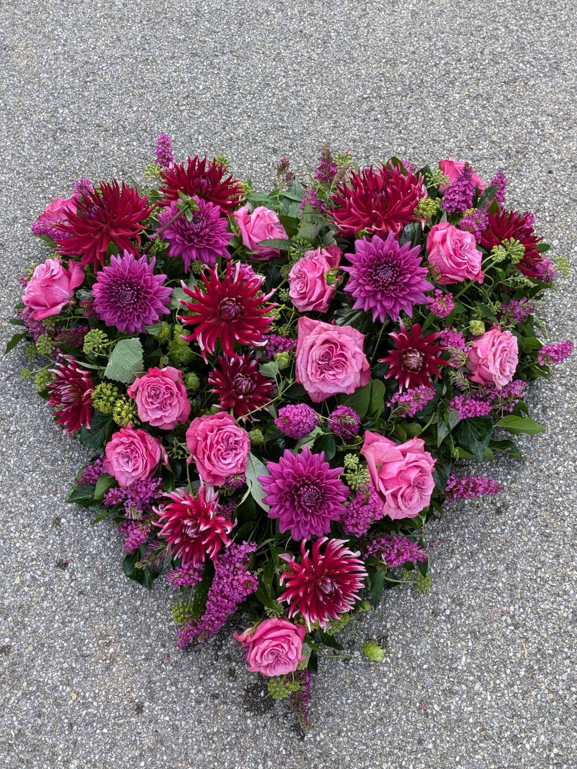 Bunter Blumenstrauß mit dicht als Herz angeordneten Blüten auf einer Oberfläche