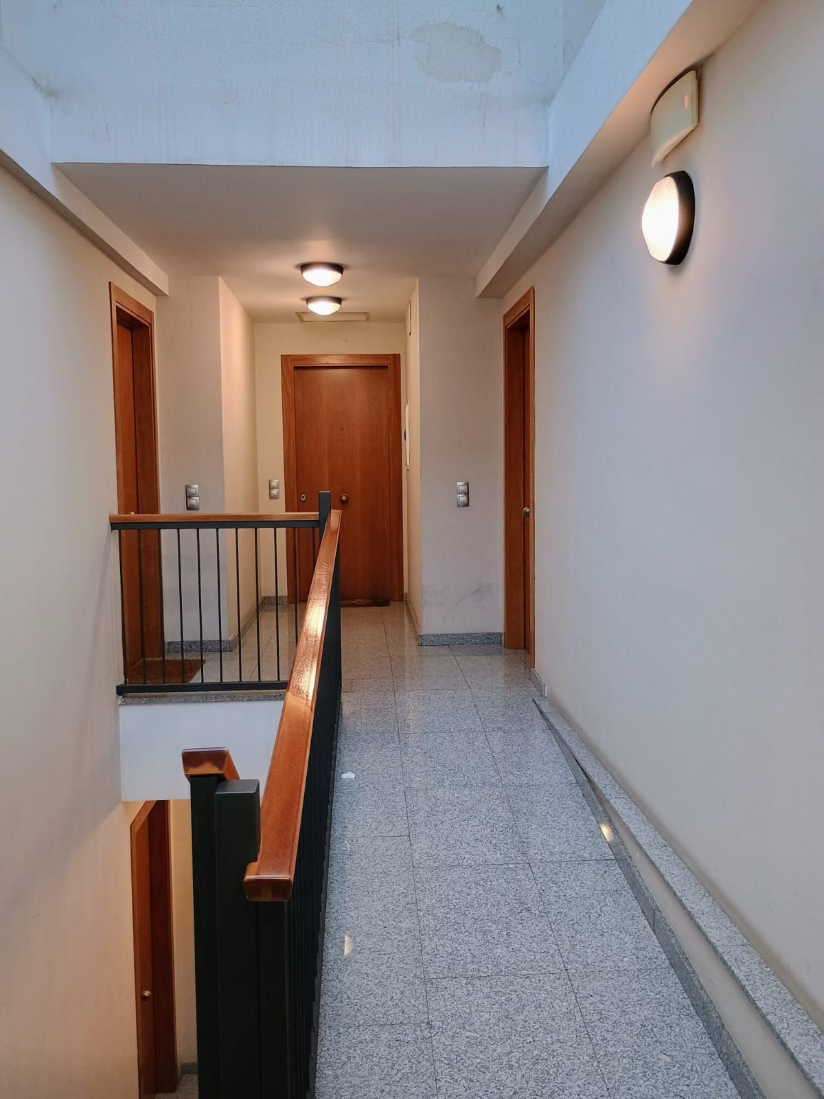 Un largo pasillo con escaleras y una luz en la pared.