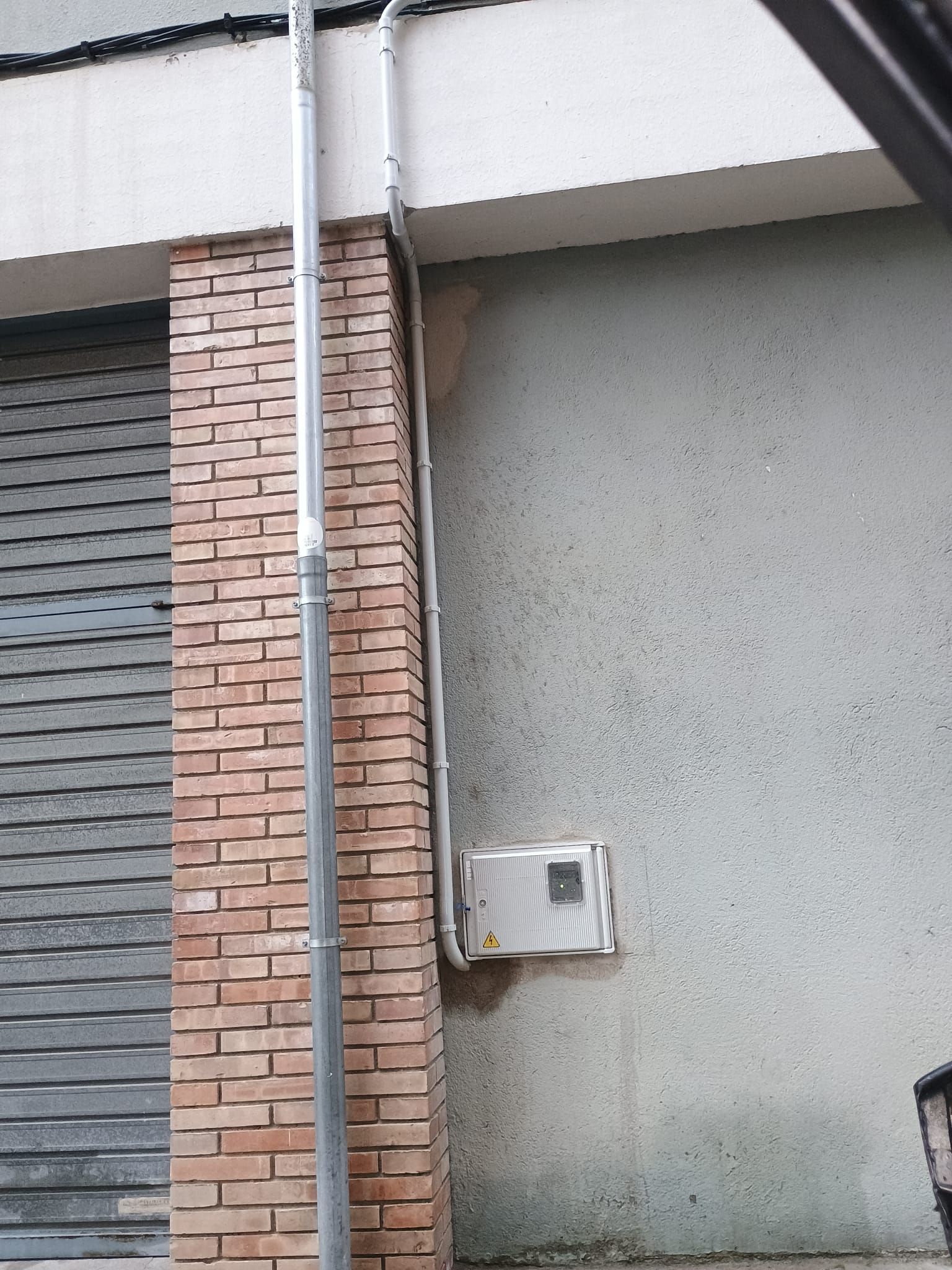 Una pared de ladrillos con un tubo de metal colgando de ella