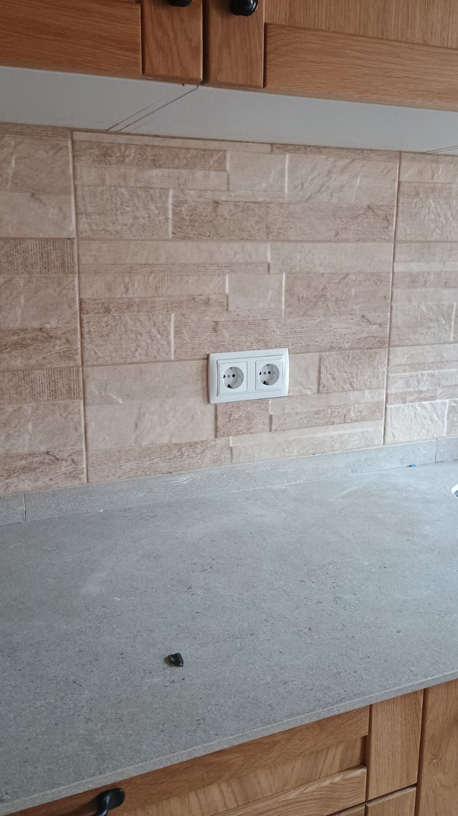 Una cocina con una pared de ladrillo y una encimera gris.
