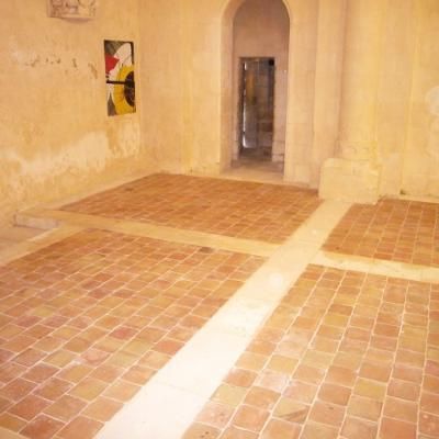 Pièce en pierre brute avec sol en terre cuite et une porte dans le mur du fond