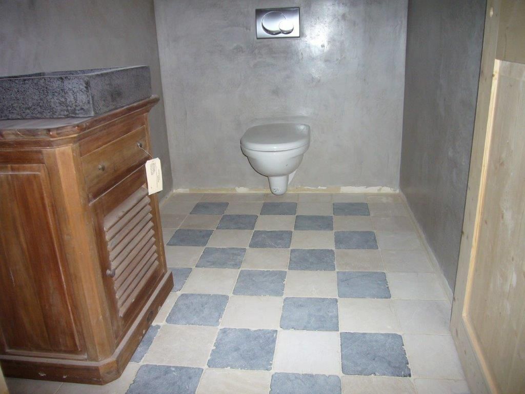 Petits toilettes avec WC et sol carrelé gris-bleu à damier, vus depuis l'entrée.