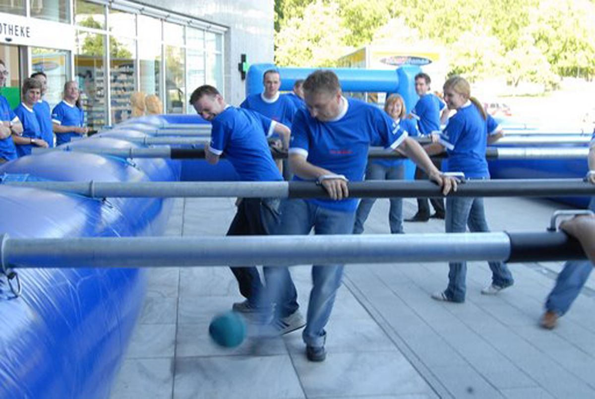 Eine Gruppe von Menschen in blauen Hemden spielt Tischfußball