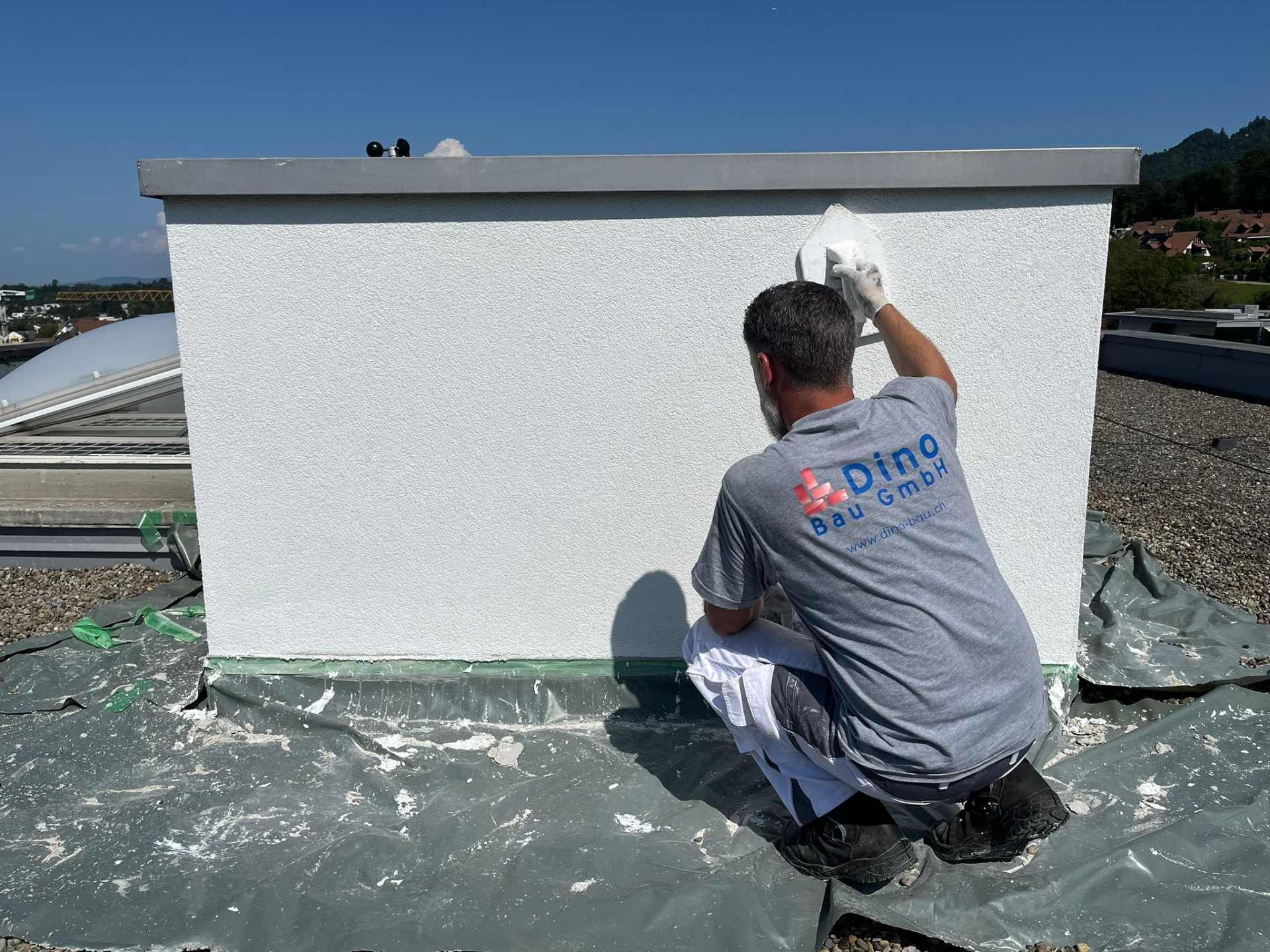 Bauarbeiter verputzt Mauer auf einem Flachdach