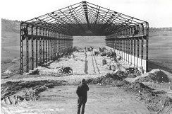 Una fotografía en blanco y negro de un hombre parado frente a un edificio en construcción.