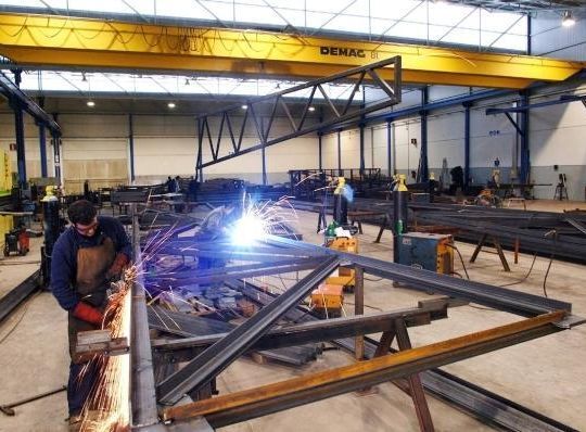 Un hombre está soldando una estructura metálica en una fábrica.