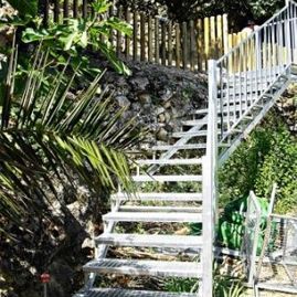 Un conjunto de escaleras de metal que conducen a una valla en un jardín.