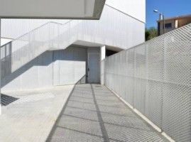 Un edificio blanco con escaleras y una valla delante.
