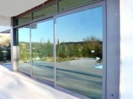 Una gran puerta corrediza de vidrio con un reflejo de una piscina en la ventana.