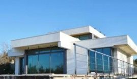 Una casa blanca moderna con un balcón y un cielo azul al fondo.