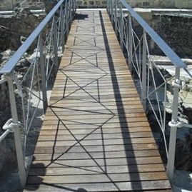 Un puente de madera con barandilla de metal sobre un río.