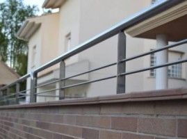 Una pared de ladrillos con una barandilla de metal delante de una casa.