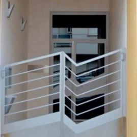 Una imagen de un balcón con una barandilla blanca y una puerta.