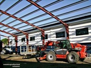 Un tractor rojo está estacionado frente a un edificio en construcción.