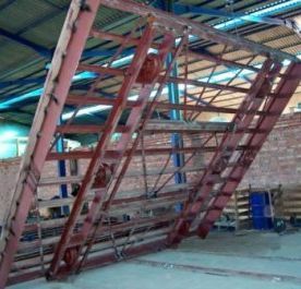 Una gran escalera de metal en un almacén con una pared de ladrillos al fondo.