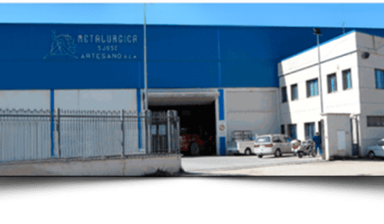 Un edificio azul y blanco con coches aparcados delante.