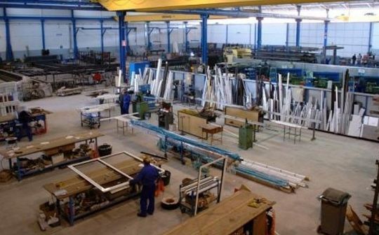 Un hombre con una camisa azul está de pie en una fábrica.