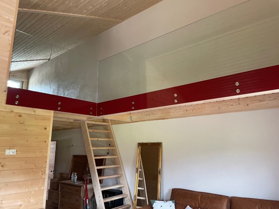 Loft mit rotem Geländer und Holztreppe, Innenansicht.