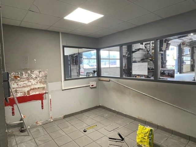 Pièce rénovée aux murs gris, avec de grandes fenêtres, un sol carrelé et des débris de construction.