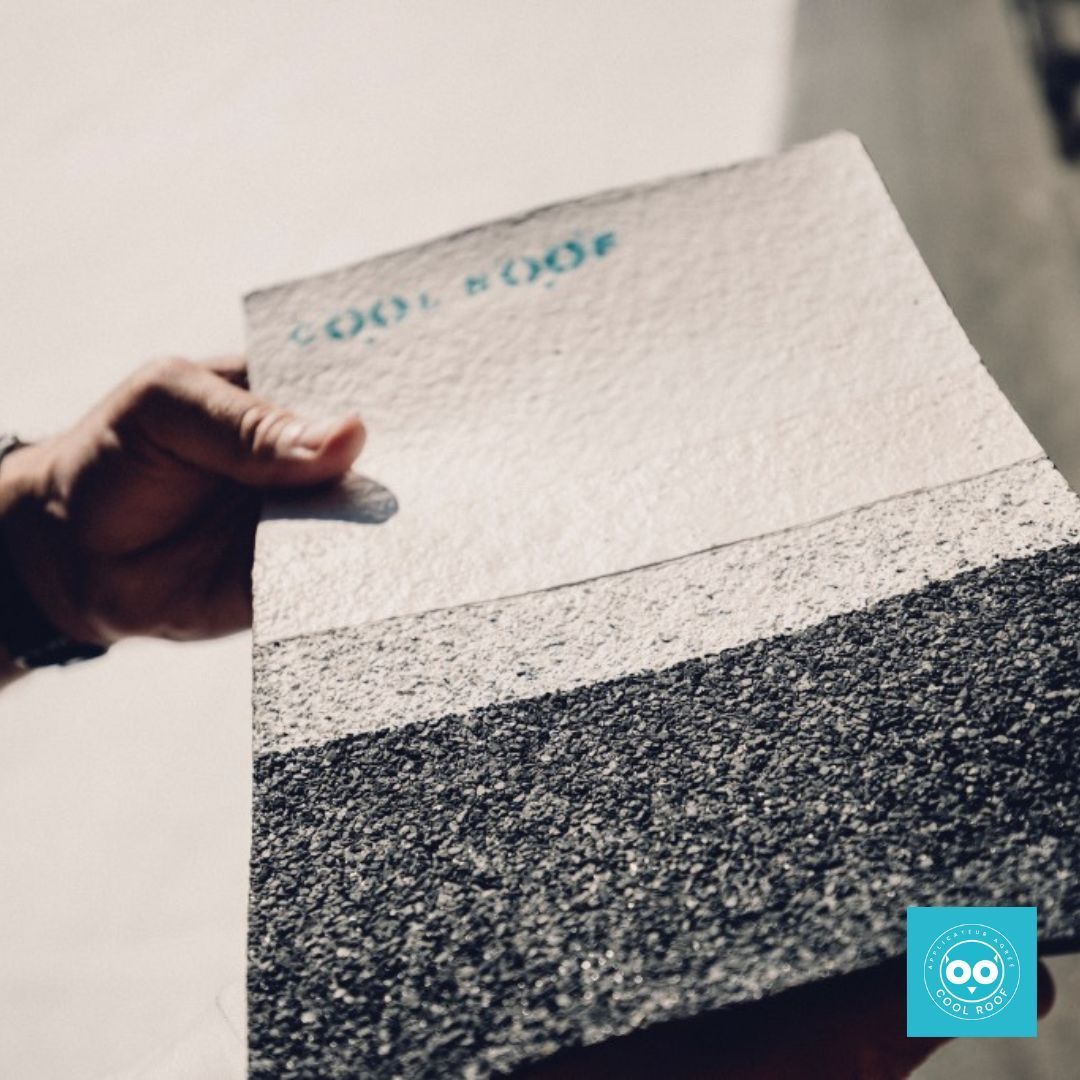 Une personne tenant un échantillon de matériau de toiture multicouche, montrant différentes textures et nuances de gris.