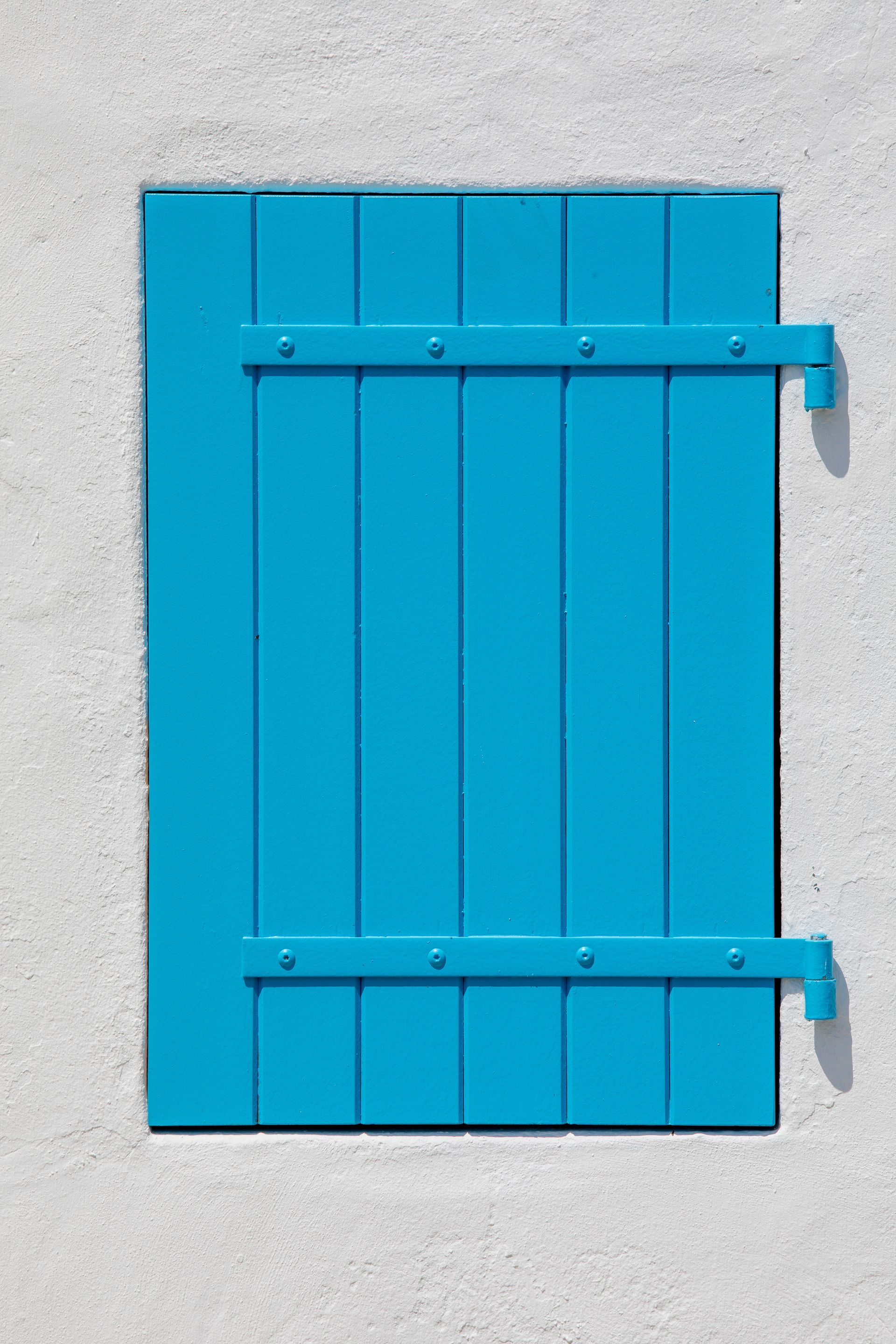 Volet en bois bleu sur un mur en stuc blanc.