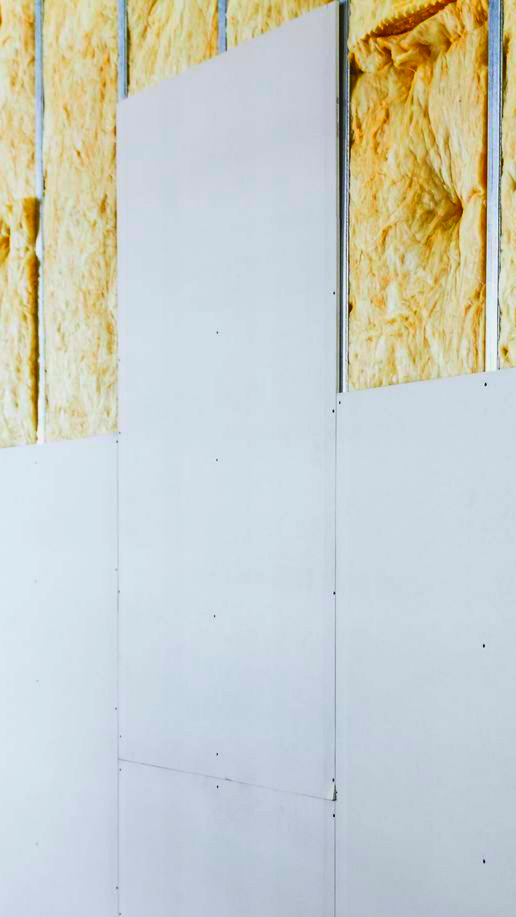 Pose de plaques de plâtre sur un mur avec isolation entre les montants.