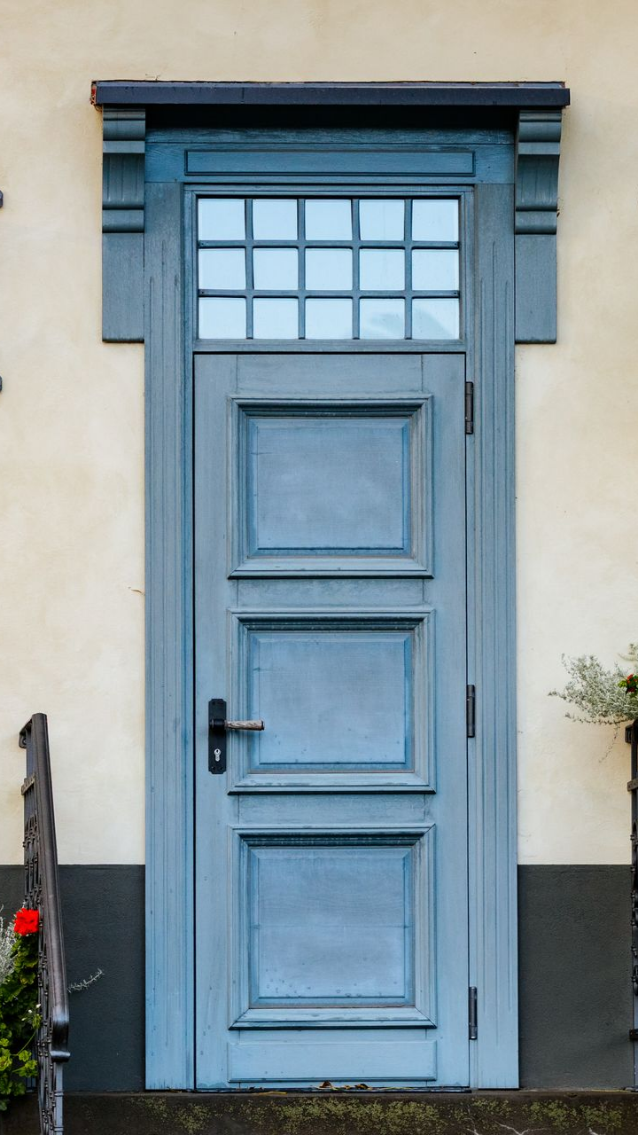 Porte bleue à panneaux carrés et vitres, adossée à un mur couleur crème.