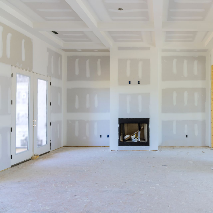 Pièce inachevée avec cloisons sèches. Cheminée au centre. Portes-fenêtres à gauche. Plafond à caissons.