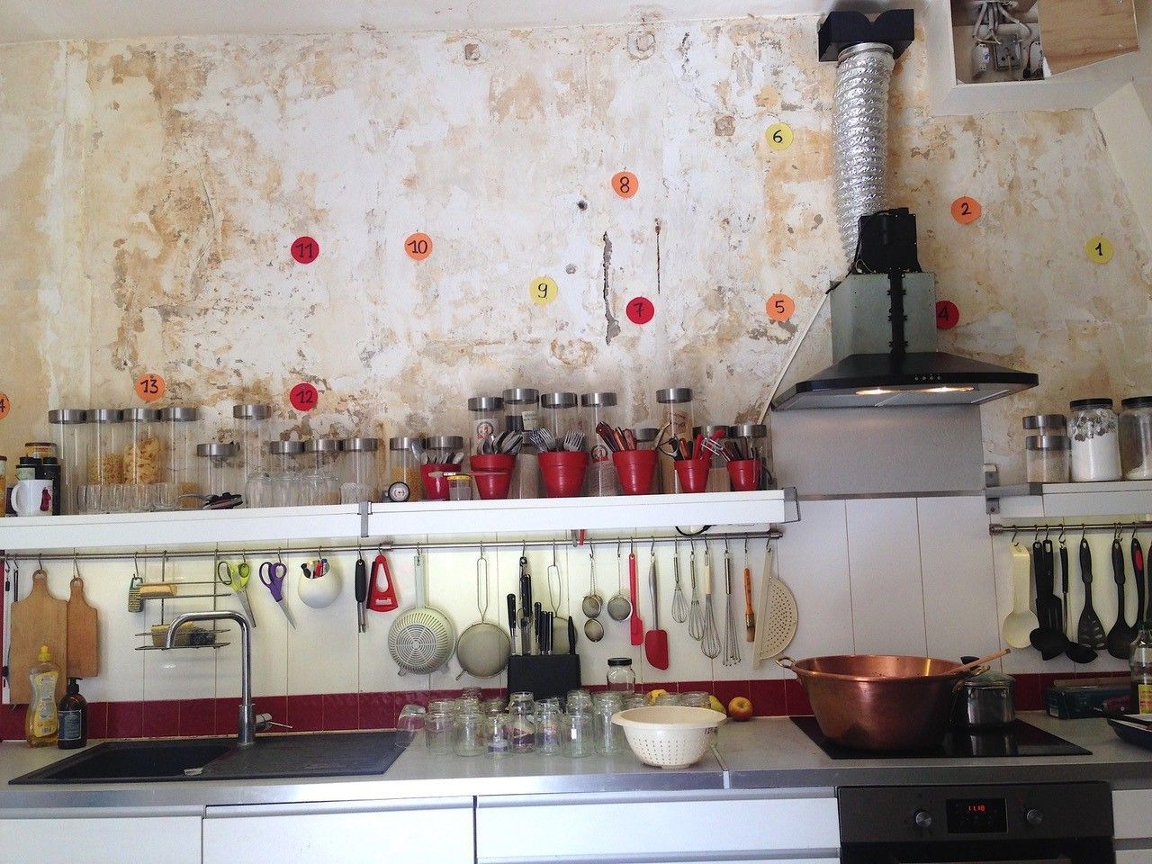 Cuisine avec mur patiné, électroménagers en acier inoxydable et ustensiles de cuisine en cuivre.