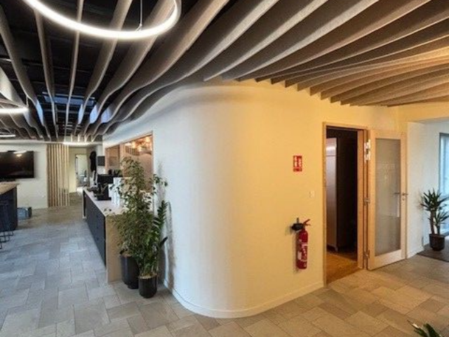 Intérieur de bureau moderne avec mur blanc incurvé, plafond ouvert et porte.