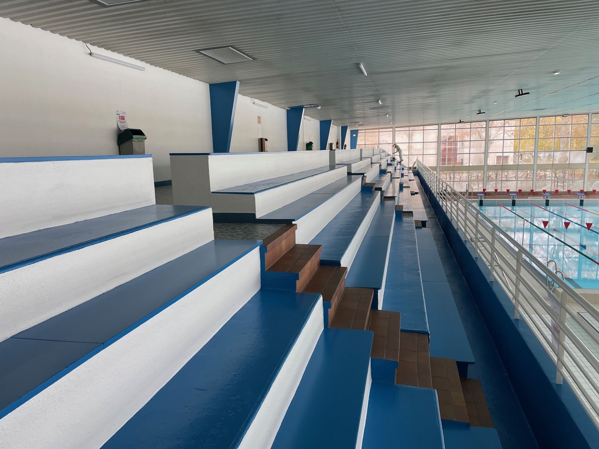 Piscine intérieure avec gradins ; couleurs bleu et blanc.