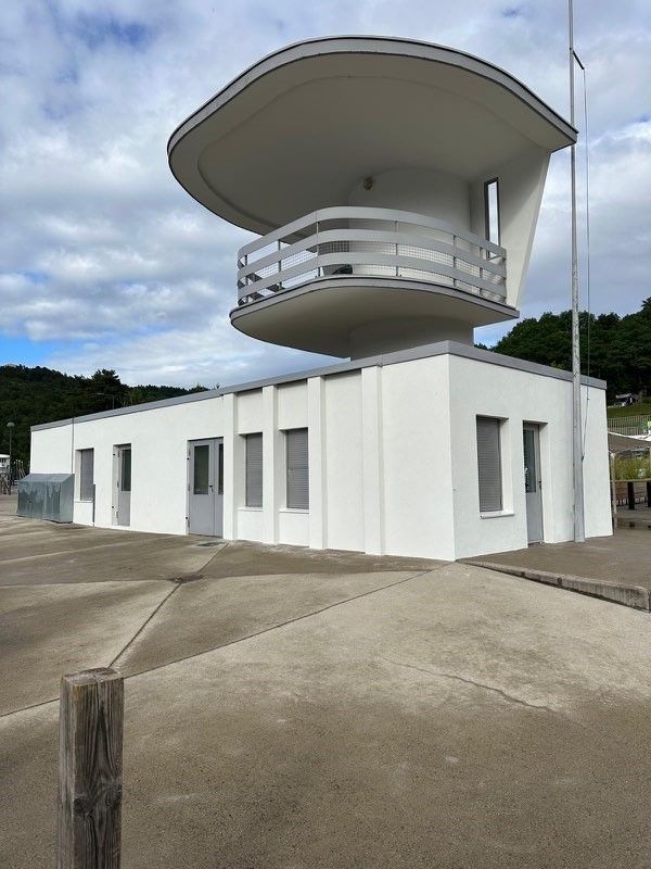 Bâtiment Art déco blanc surmonté d'une tour d'observation incurvée ; ciel nuageux.