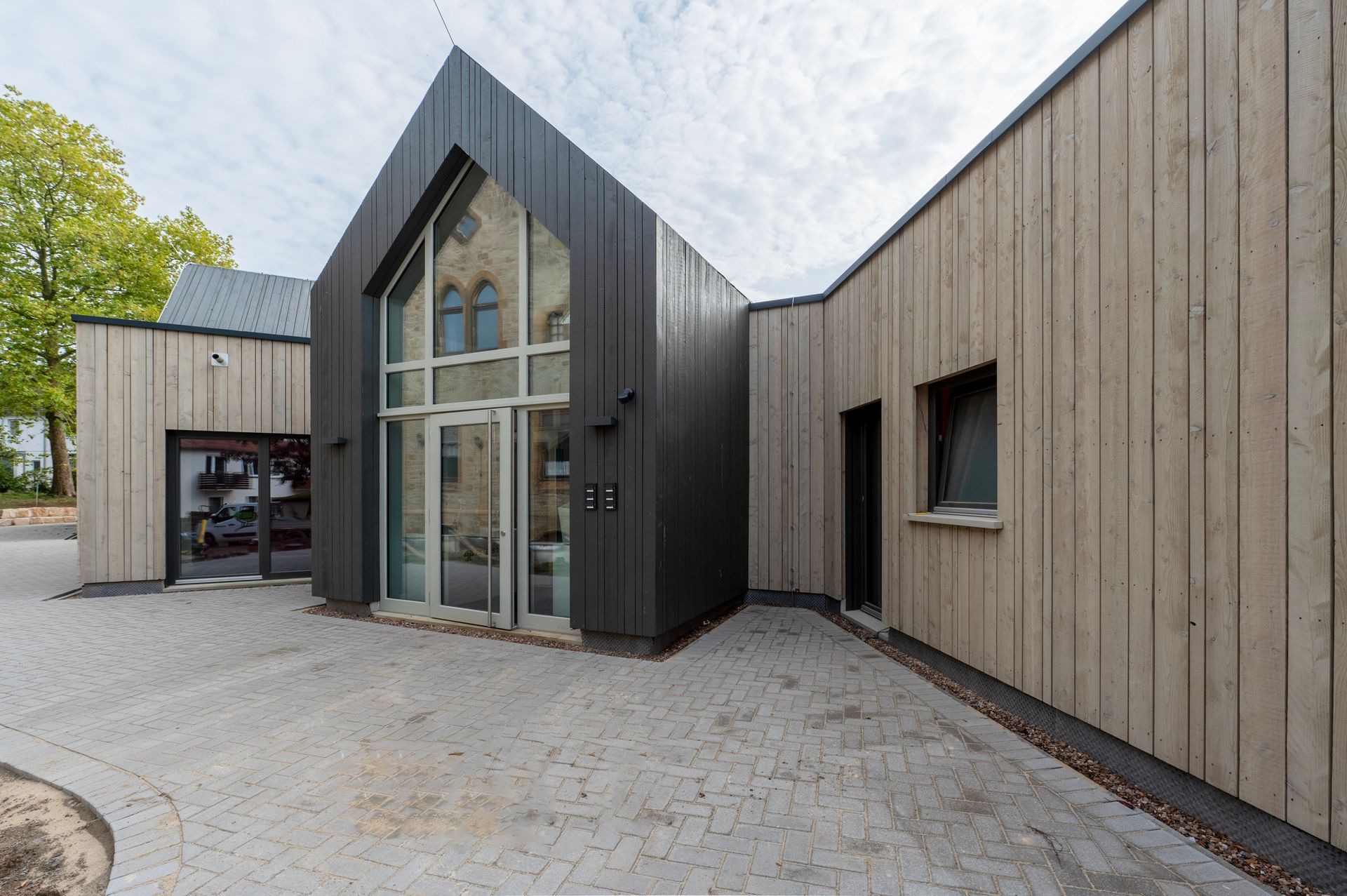 Holzverkleidung an einem Falachdachbau mit einem Spitzdacheingang